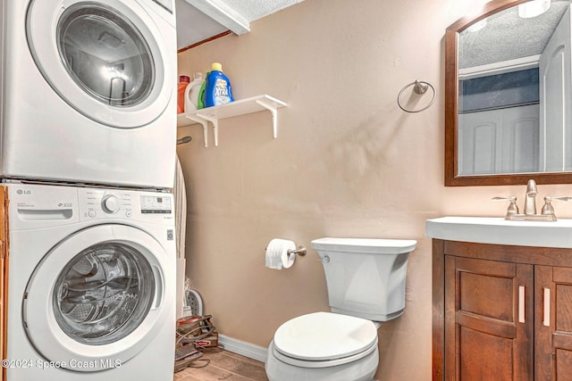 clothes washing area with sink, stacked washer / dryer, a textured ceiling, and light wood-type flooring