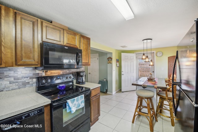 kitchen featuring black appliances, decorative light fixtures, light tile patterned floors, a textured ceiling, and tasteful backsplash