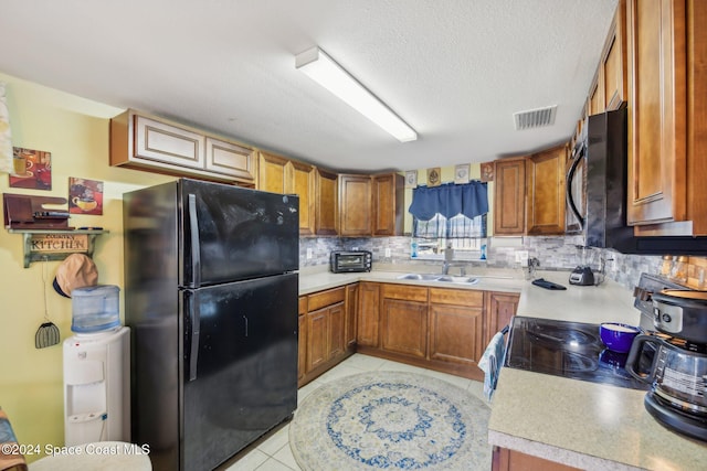 kitchen featuring backsplash, sink, black appliances, light tile patterned floors, and a textured ceiling