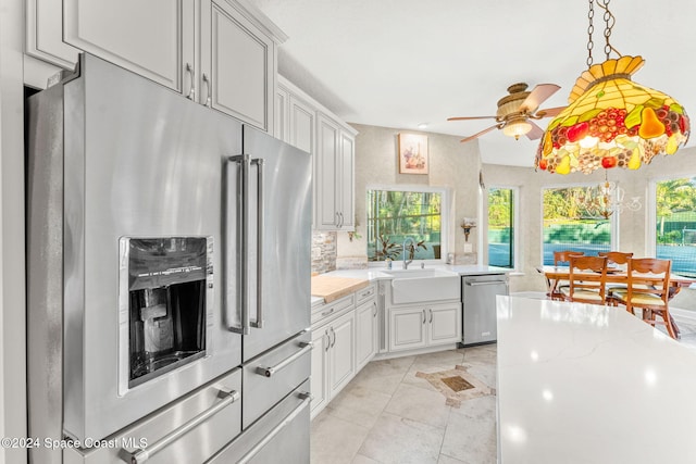 kitchen with decorative backsplash, ceiling fan, appliances with stainless steel finishes, sink, and light stone counters