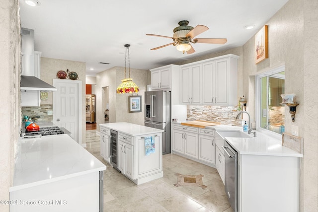 kitchen featuring wall chimney range hood, wine cooler, a kitchen island, appliances with stainless steel finishes, and white cabinetry