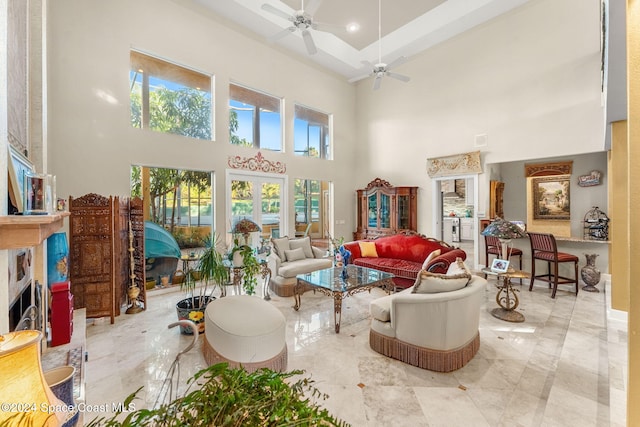 living room featuring a high ceiling, a healthy amount of sunlight, and ceiling fan