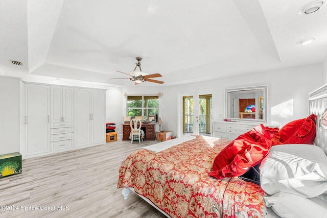 bedroom featuring light hardwood / wood-style flooring, french doors, a raised ceiling, and ceiling fan