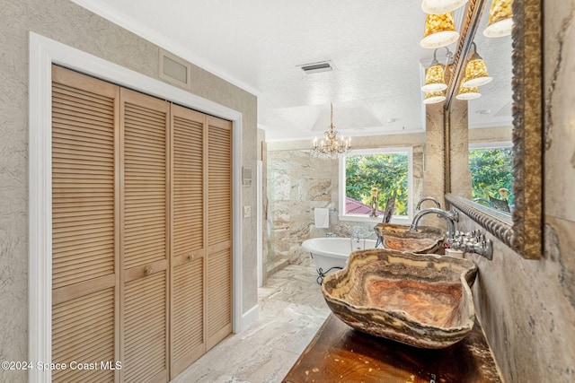 bathroom with crown molding, a textured ceiling, an inviting chandelier, and a bathing tub