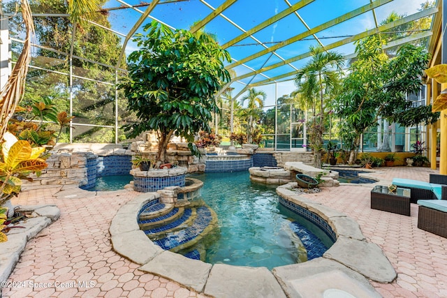 view of swimming pool featuring a hot tub, a patio, and glass enclosure