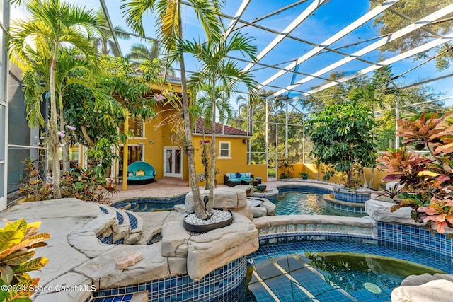 view of pool featuring an in ground hot tub, a patio area, and glass enclosure