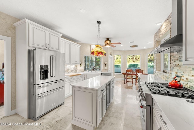 kitchen with a kitchen island, white cabinets, decorative light fixtures, appliances with stainless steel finishes, and tasteful backsplash