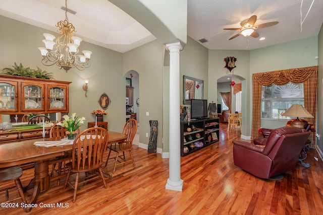 dining area with decorative columns, light hardwood / wood-style flooring, and ceiling fan with notable chandelier