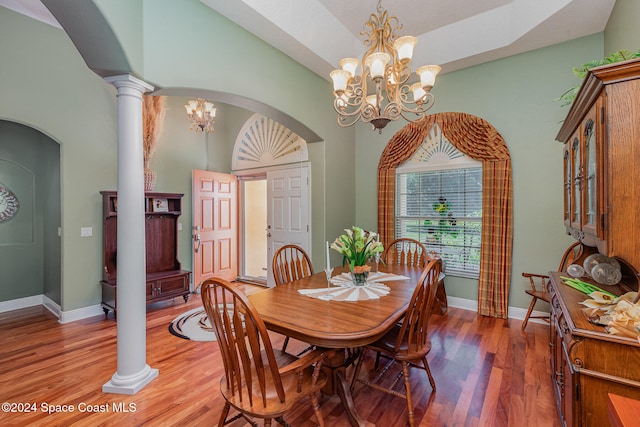 dining space featuring a notable chandelier, ornate columns, and wood-type flooring