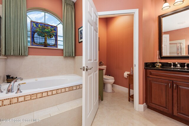 bathroom featuring vanity, tiled tub, and toilet