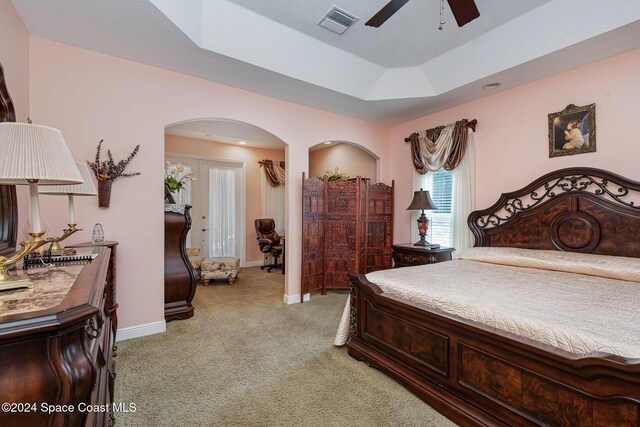 bedroom with light carpet, a raised ceiling, and ceiling fan