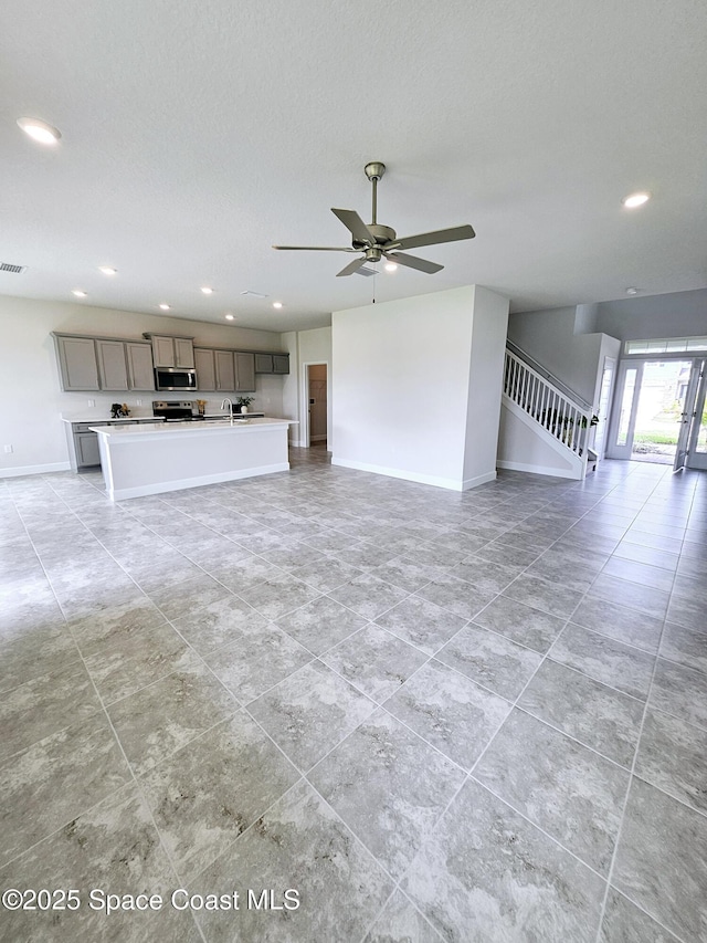 unfurnished living room with sink and ceiling fan