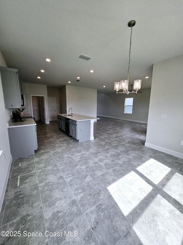 kitchen with an inviting chandelier, sink, gray cabinetry, decorative light fixtures, and an island with sink