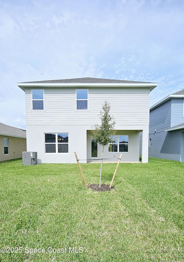 rear view of house with a lawn and central air condition unit