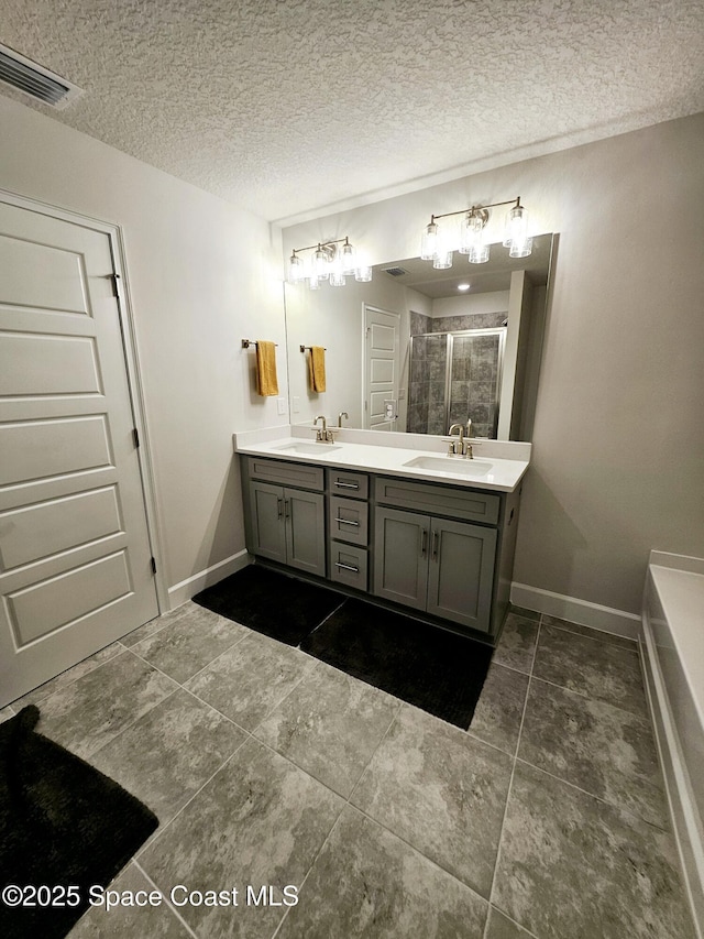 bathroom with a textured ceiling, vanity, and walk in shower