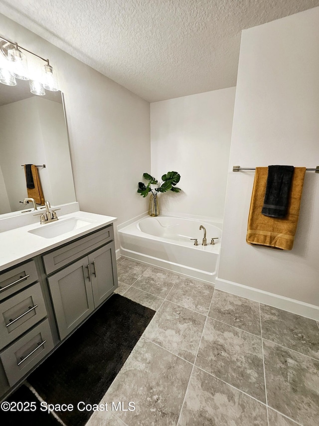 bathroom with a textured ceiling, a tub to relax in, and vanity