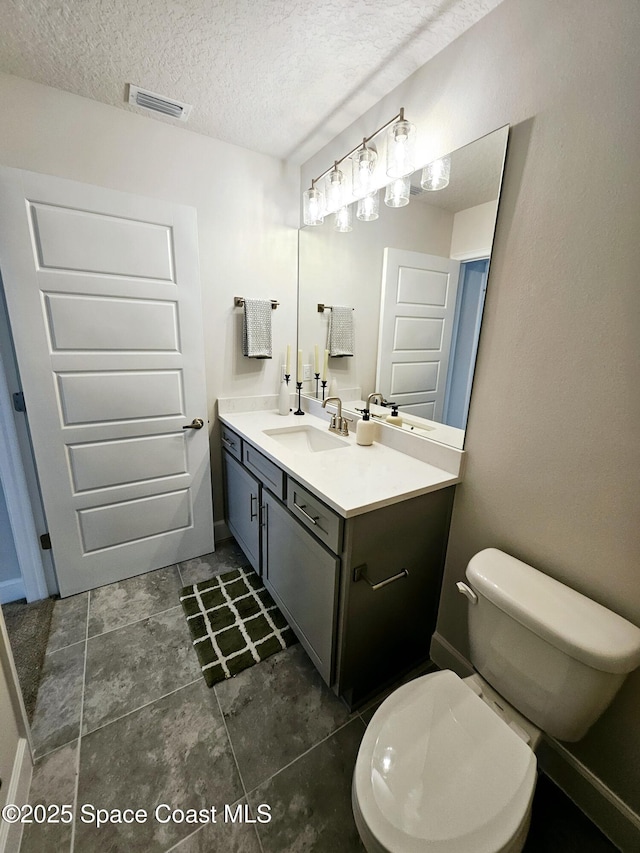 bathroom featuring toilet, vanity, and a textured ceiling