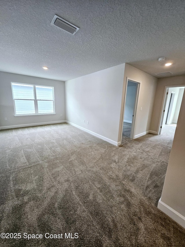 spare room featuring a textured ceiling and light colored carpet