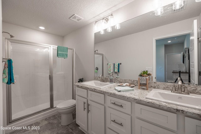 bathroom with tile patterned floors, an enclosed shower, a textured ceiling, vanity, and toilet