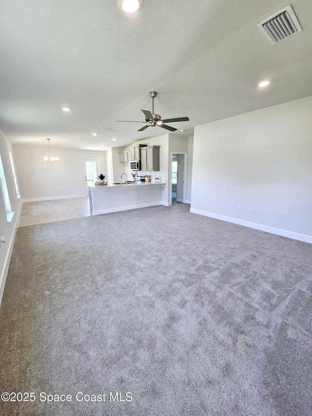 unfurnished living room featuring sink, ceiling fan with notable chandelier, carpet, and a textured ceiling