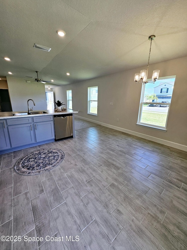 kitchen with ceiling fan with notable chandelier, decorative light fixtures, sink, stainless steel dishwasher, and a textured ceiling