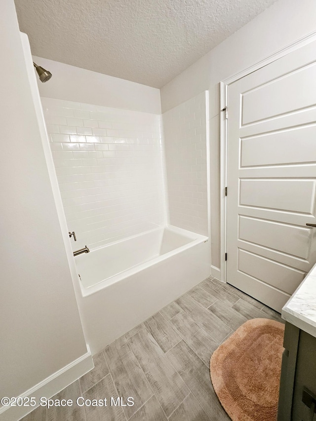 bathroom featuring vanity, tiled shower / bath combo, and a textured ceiling