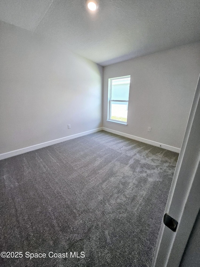 empty room with dark carpet and a textured ceiling