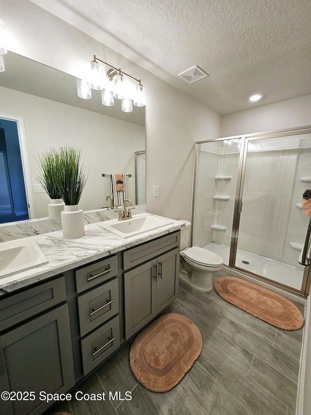 bathroom featuring an enclosed shower, vanity, a textured ceiling, and toilet