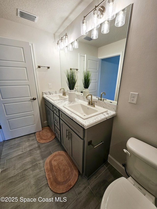 bathroom featuring vanity, toilet, and a textured ceiling