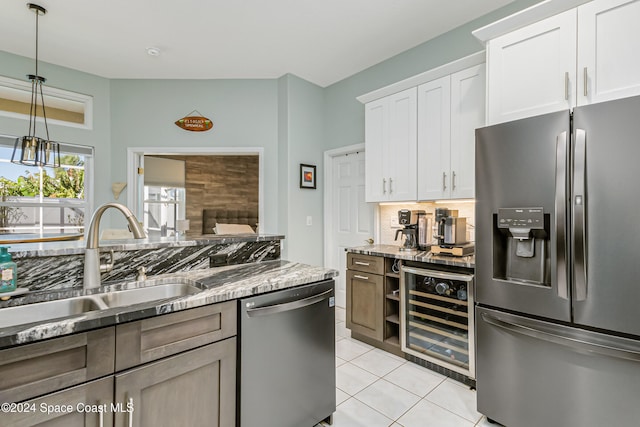 kitchen with wine cooler, white cabinets, light stone counters, sink, and stainless steel appliances