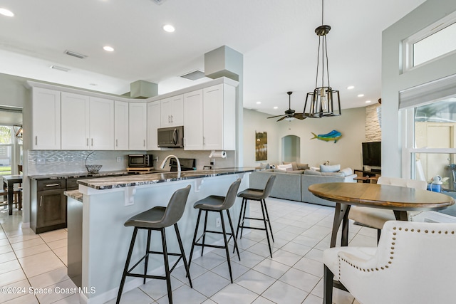 kitchen featuring kitchen peninsula, white cabinetry, hanging light fixtures, and light tile patterned floors