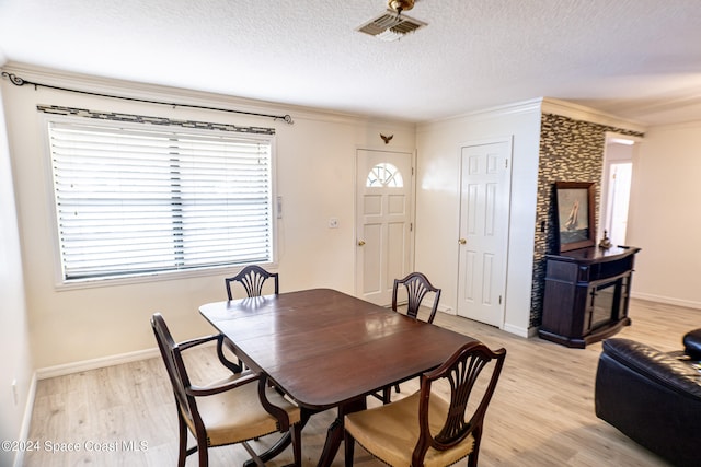 dining room featuring crown molding, a textured ceiling, and light hardwood / wood-style floors