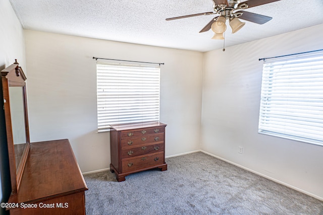 carpeted bedroom featuring ceiling fan and a textured ceiling