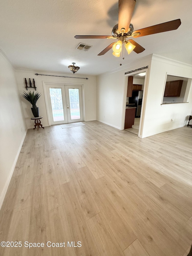 unfurnished living room with french doors, crown molding, and light wood-type flooring