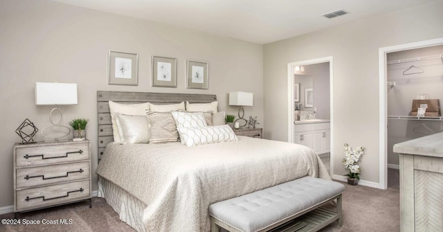 bedroom featuring dark colored carpet, a closet, a walk in closet, sink, and ensuite bathroom