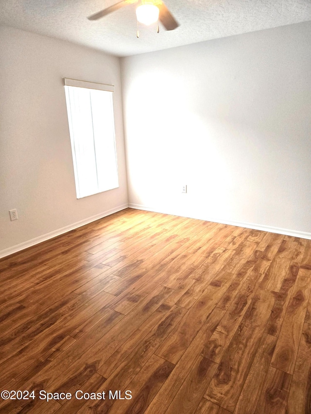 empty room with a textured ceiling, dark hardwood / wood-style floors, and ceiling fan