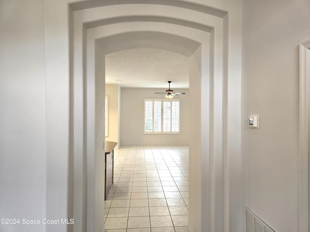 corridor with light tile patterned flooring and a textured ceiling