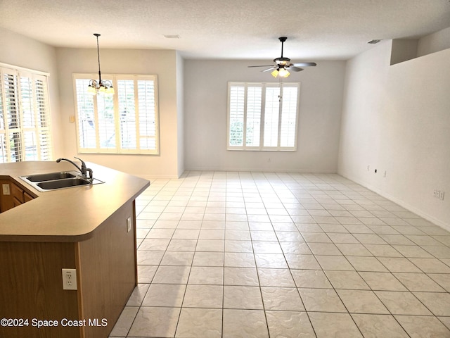 kitchen with sink, hanging light fixtures, ceiling fan with notable chandelier, and light tile patterned floors