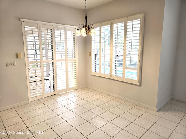 unfurnished room with light tile patterned floors, a wealth of natural light, and an inviting chandelier