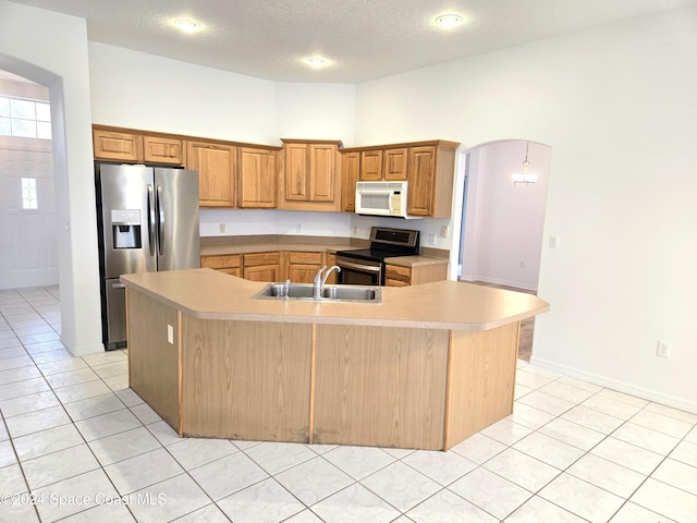 kitchen with a large island with sink, a textured ceiling, appliances with stainless steel finishes, and sink