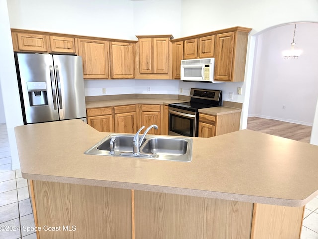 kitchen featuring a center island with sink, sink, pendant lighting, light tile patterned floors, and appliances with stainless steel finishes