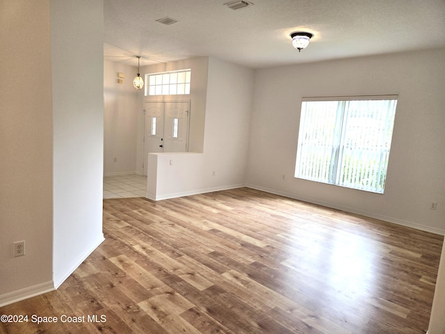 unfurnished living room featuring light hardwood / wood-style flooring and a textured ceiling