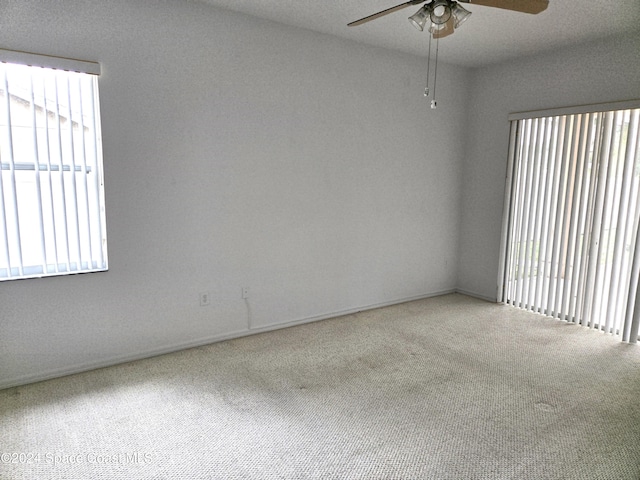 carpeted empty room featuring ceiling fan, a textured ceiling, and plenty of natural light