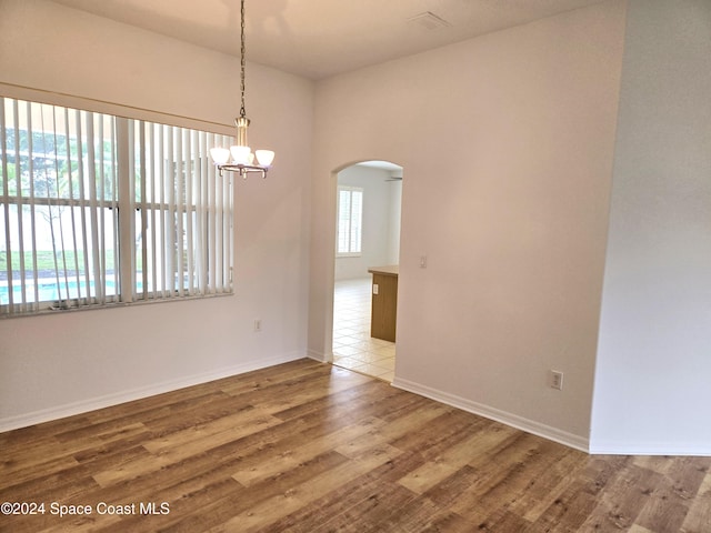 unfurnished room featuring a chandelier and hardwood / wood-style flooring