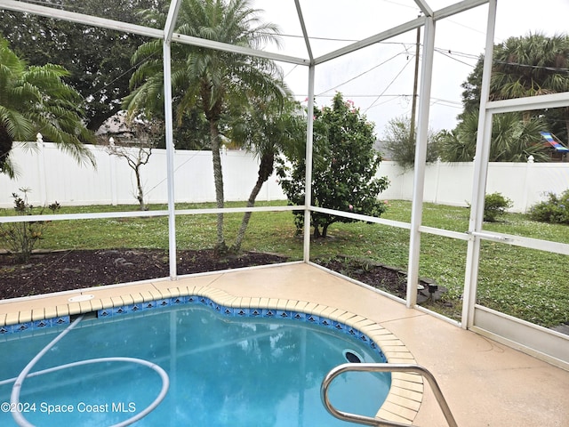 view of swimming pool featuring a lanai and a lawn