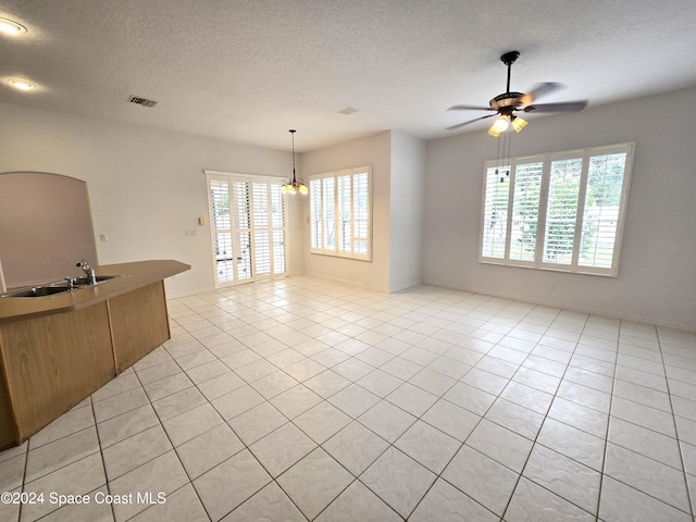 interior space with light tile patterned flooring, sink, ceiling fan with notable chandelier, and a wealth of natural light