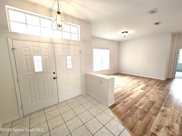 foyer entrance featuring a textured ceiling and light hardwood / wood-style flooring