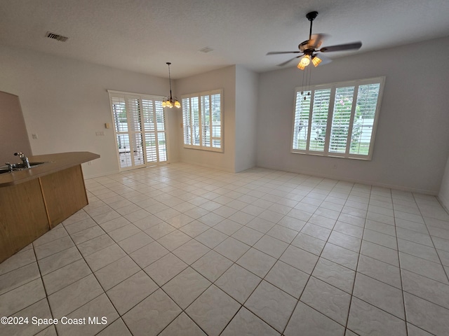 interior space with sink, a textured ceiling, ceiling fan with notable chandelier, and light tile patterned floors