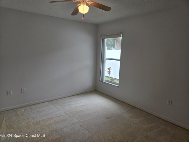 unfurnished room featuring a textured ceiling, light colored carpet, and ceiling fan