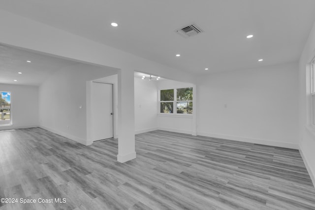 spare room with a wealth of natural light, light hardwood / wood-style flooring, and a notable chandelier